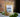 A 1oz sample bag of Megan & Co. Hope + Love tea on a white marble table, staged with green leaves at the base and a blurred brick wall in the background.