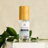 A clear spray bottle labeled 'AWAKE' with a wooden cap, surrounded by green leaves on a white marble surface.