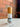 Megan & Co. Awake spritzer in a clear bottle with a wooden cap, staged on a white marble surface against a rustic brick wall background.
