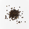 A loose cluster of whole black peppercorns, showing their characteristic wrinkled, dark brown to black outer husks, scattered on a clean white background.