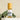 A clear spray bottle labeled 'Megan Rose Calm' containing a yellow liquid, placed on a white surface with green leaves in the background.