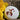 A single round, white bath bomb topped with vibrant dried rose and orange botanical petals, resting on a rustic stone surface next to a bright yellow flower.