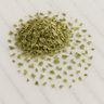 A small mound of dried, sage-green eucalyptus leaf pieces, scattered across a light grey veined marble surface.