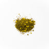 A small mound of dried goldenseal root pieces, featuring a vibrant mustard-yellow color with small woody fragments and fine, fibrous shreds, centered on a clean white surface.
