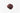 A small, centered mound of dried hibiscus flower petals, featuring a deep burgundy and crimson color with a slightly curled, leathery texture on a plain white surface.