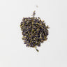 A small, tidy mound of dried lavender flower buds, displaying a deep purple-blue hue with small green stem fragments, isolated on a clean white background.