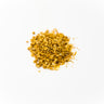 A small mound of dried lemon peel granules, showing a vibrant yellow-gold color and coarse texture, staged on a clean white background.