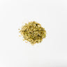 A small mound of dried linden aerial parts, consisting of thin, flake-like green and tan leaf fragments, staged on a clean white background.