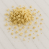 A cluster of delicate, pale-cream dried meadowsweet flowers scattered across a light-colored marble surface with soft grey veining.