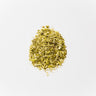 A small mound of dried Oregon grape root, featuring small, coarse yellow-tan woody chips and fragmented root pieces, staged on a clean white background.
