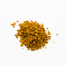 A small mound of dried turmeric root pieces, featuring small, irregular chunks in a deep golden-yellow to orange-brown color, placed on a clean white background.