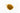 A small mound of dried turmeric root pieces, featuring small, irregular chunks in a deep golden-yellow to orange-brown color, placed on a clean white background.