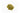 A small mound of dried yerba mate leaves, consisting of finely chopped herbal flakes in various shades of olive and forest green. The mixture is placed on a clean white background and shows a dry, slightly leathery texture.