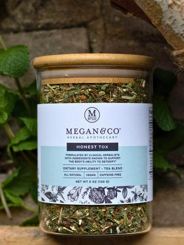 Jar of Megan & Co. Honest Tox tea blend with a wooden lid on a natural background.