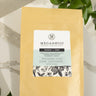 Megan & Co. Mama + One product packaging on a marble surface with green leaves.