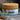 Megan & Co. Chest Re-Leaf herbal salve in a glass jar with a bamboo lid on a rough stone surface with eucalyptus leaves on the side and a blurry brick background.