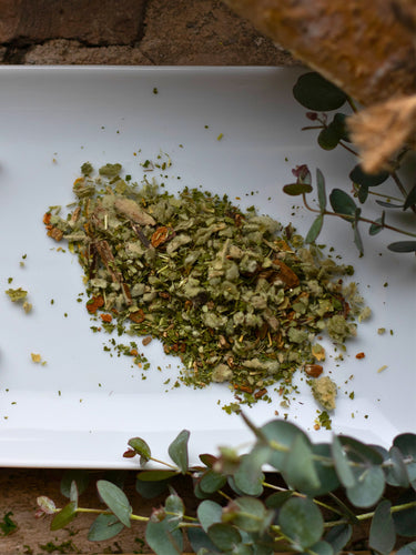 Loose leaf Chest Re-Leaf herbal tea blend on a white plate with eucalyptus leaves and a branch by the side.