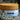 Megan & Co. Heel + Knuckle herbal salve jar with a bamboo lid on a rough stone surface with eucalyptus leaves on the side and a blurry background.