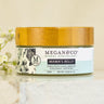 Megan & Co. Mama's Belly Herbal Whip in a glass jar with a bamboo lid on a white marble surface with white Baby's Breath flowers on the side.