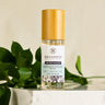 Megan & Co. Sacred Bloom Essence Spritzer with a bamboo cap on layered white marble stones with fresh green leaves at the base.