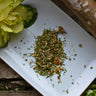 Sinus Re-Leaf loose leaf herbal tea on a white plate, staged with flowers and a natural tree branch, showcasing ingredients like elderflower and peppermint.