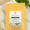 A 1oz sample bag of Megan & Co. Slumber tea on a marble surface, staged with green leaves.