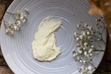 A smooth scoop of creamy white Soothe herbal whip on a ceramic plate with baby's breath flowers on each side.