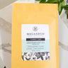 A 1oz sample bag of Megan & Co. Tummy Time tea on a marble surface, staged with green leaves.
