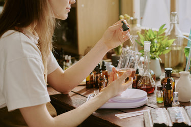 Person working with various bottles and containers on a table, possibly in a laboratory setting.