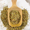 MEGAN & CO. Mocha Mint Loose-leaf tea displayed in wooden scoop on marble table.