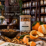 Glass jar with dried orange peel set on a table in a room with more glass jars in the background. 