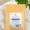 A packaged sample of Peaceful Prairie tea blend by MEGAN & CO. placed on a counter with a leafy garnish.
