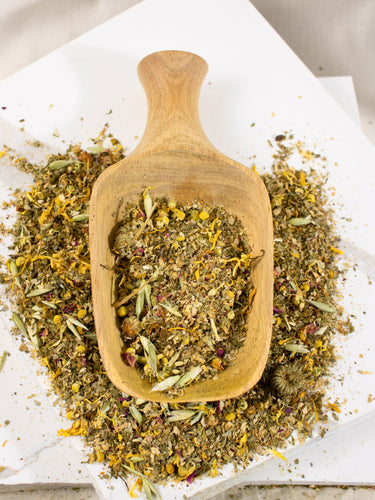 MEGAN & CO. Loose-leaf herbal tea, Peaceful Prairie blend, dispensed into wooden scoop on a marble white counter.