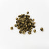 A small cluster of hand-rolled jasmine tea pearls, featuring a marbled pattern of silvery-white downy buds and dark green tea leaves, centered on a clean white surface.