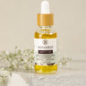 A small bottle of Happy Ear Herbal Oil with a dropper, placed on a soft surface alongside decorative flowers.
