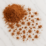 A small mound of rich, reddish-brown cacao powder scattered across a white marble surface.