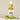 A small clear glass bottle with a dropper filled with yellow liquid, labeled 'Megan and Co R + R Herbal Oil', displayed on a white textured surface with a green leaf beside it.