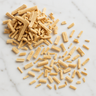 A 28g scattering of dried, light-tan ashwagandha root segments on a white marble surface.
