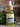 Bottle of Megan & Co. Revival Hair Oil with a wooden dropper on a stone surface with greenery.
