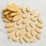 A 28g scattering of dried, oval-shaped astragalus root slices on a white marble surface.