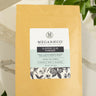 Megan & Co slippery elm powder package on a marble surface with green leaves.