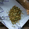 Dry herbs on a white plate with small white flowers around