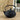 A textured black hobnail cast iron teapot with a top handle, staged on a wooden surface with a blurred indoor background.