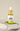 A glass jar with a dropper contains yellow liquid, placed on a white surface with a green leaf in the background. The label reads 'Transform'.