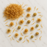 Bright yellow dried calendula petals and whole flower heads scattered across a white marble surface.