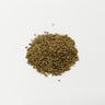 A 28g small mound of dried, oval-shaped brown anise seeds centered on a solid white surface.