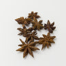 A 28g scattering of whole brown star anise pods on a clean, solid white surface.