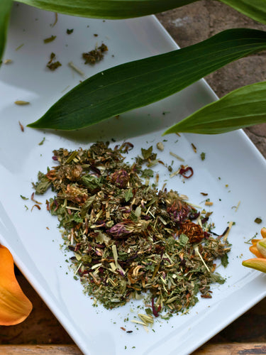 Dried herbs on a white plate with green leaves