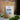A 1oz sample bag of Megan & Co. Hope + Love tea on a white marble table, staged with green leaves at the base and a blurred brick wall in the background.